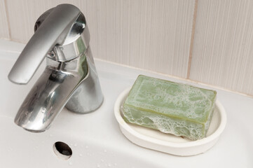 Green soap in foam in white soap dish in bathroom. Washing hads concept
