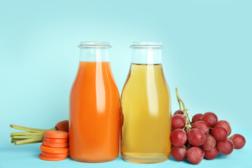 Bottles of delicious juices and fresh ingredients on light blue background