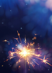 Glittering burning sparkler against fireworks background