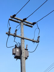 Electrical transformer to electrical concrete pole against the blue sky