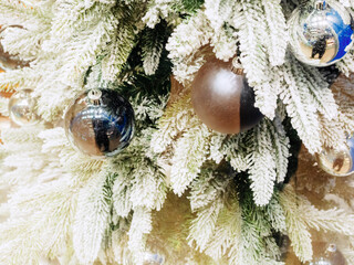 Shiny christmas balls hang on fir branches with artificial snow
