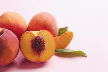 Fototapeta na wymiar Whole and cut fresh ripe peaches on pink background, closeup