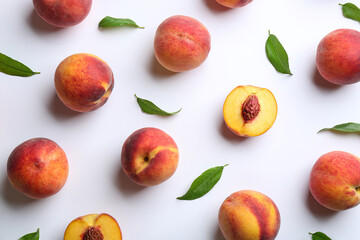 Fresh ripe peaches and green leaves on white background, flat lay