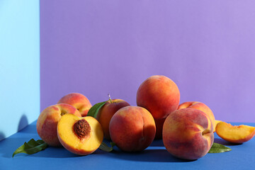 Fresh ripe peaches and green leaves on color background