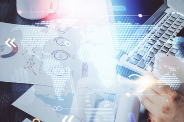Double exposure of world map hologram with man working on computer on background. Concept of worldwideweb.