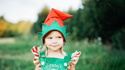 Child waiting for Christmas in wood in juli. portrait of little girl near christmas tree. Baby...