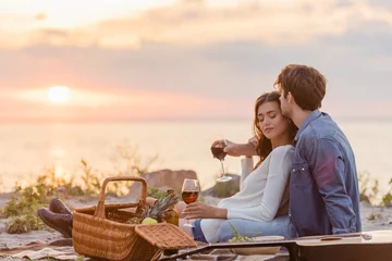 Fotobehang Selective focus of couple holding glasses of wine during picnic on beach at evening © LIGHTFIELD STUDIOS