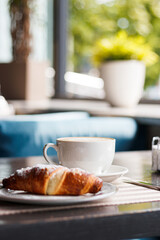 morning coffee with a croissant on the summer terrace. Breakfast with cup of cappuccino