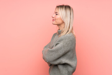 Young blonde Russian woman over isolated pink background in lateral position