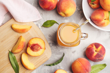 Natural peach juice and fresh fruits on grey table, flat lay