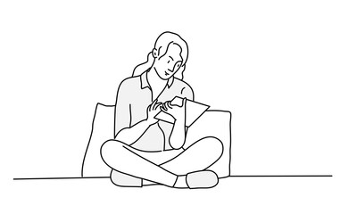 Young woman is sitting on sofa in lotus position and using tablet.