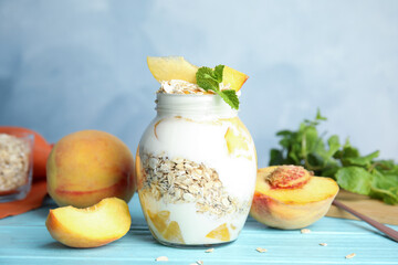 Tasty peach dessert with yogurt and granola on light blue wooden table