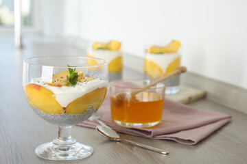Tasty peach dessert with yogurt and chia seeds served on wooden table. Space for text
