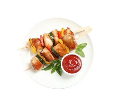 Delicious chicken shish kebabs with vegetables and ketchup on white background, top view
