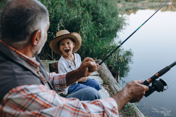 boy with his grandfather fishing on the lake