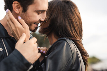 Selective focus of woman in leather jacket touching boyfriend outdoors