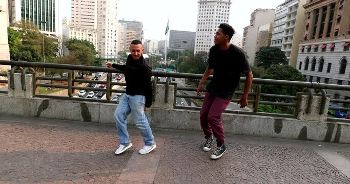Happy hispanic and black dancing in city