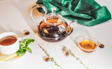 Aromatic hot green tea in a glass teapot with a warm blurry background with honey and fresh mint leaves. Served table with tea in a cafe