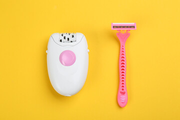 Modern epilator and shaving razor on yellow background, flat lay