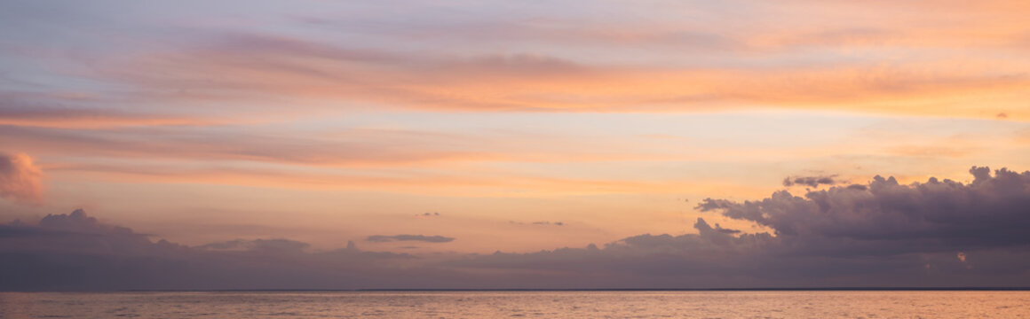 Panoramic shot of sea and cloudy sky at sunset