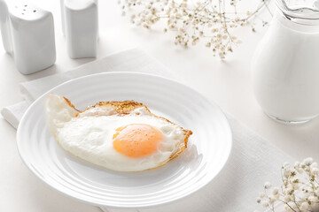 Breakfast fried eggs and a decanter of milk in a high key on a white table
