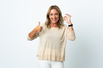 Obraz premium Middle aged blonde woman over isolated white background showing ok sign and thumb up gesture