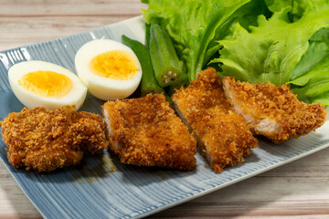 Homemade Japanese pork cutlet served with boiled egg, okra and baby leaves