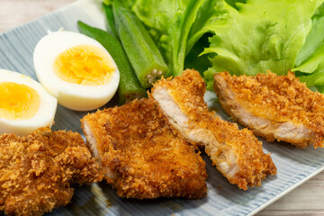 Homemade Japanese pork cutlet served with boiled egg, okra and baby leaves