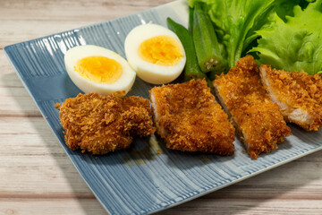 Homemade Japanese pork cutlet served with boiled egg, okra and baby leaves