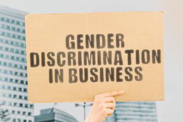 The phrase " Gender discrimination in business " on a banner in men's hand with blurred background. Human rights. Equality. Office. Work. Job. Entrepreneur. Relationship