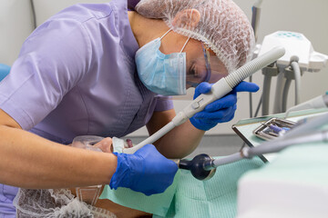 The dentist in an inconvenient position with the help of specialized instruments treats the patient's oral cavity.