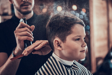 Boy in barbershop while he is sprayed with water