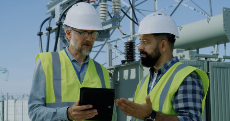 Mature engineer showing data to bearded colleague
