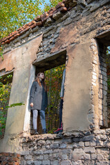 Two teenage girls stand in the window opening of an old abandoned dilapidated building.