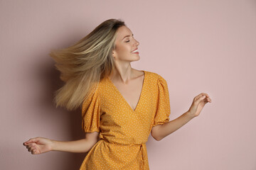 Young woman wearing stylish dress on pale pink background