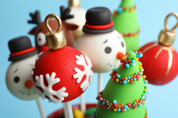 Delicious Christmas themed cake pops on light blue background, closeup