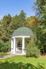 A gazebo made of white stone in a green park for rest and relaxation of visitors