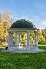 A gazebo made of white stone in a green park for rest and relaxation of visitors