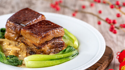 Dong Po Rou (Dongpo pork meat) in a plate with green vegetable, traditional festive food for Chinese lunar new year cuisine meal, close up.