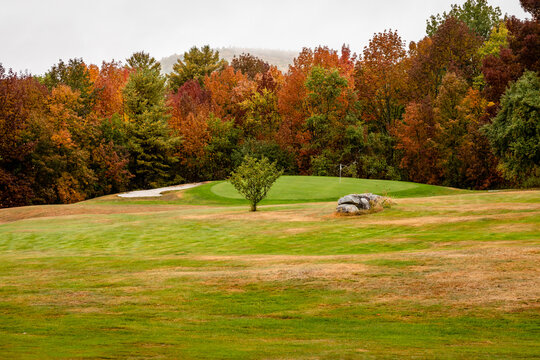 Granite rocks anchor the fairway on a golf course with fall leaf colors in bloom near Dedham, Maine