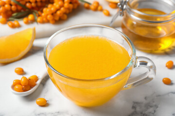 Fresh sea buckthorn tea on white marble table, closeup