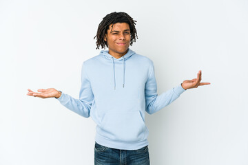 Young african american rasta man doubting and shrugging shoulders in questioning gesture.