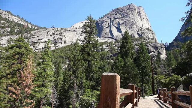 Panorama of Half Dome, Mt Broderick and Liberty Cap peaks and Nevada Fall waterfall on Merced River bridge of Mist trail in Yosemite National Park. Summer travel in California, United States.