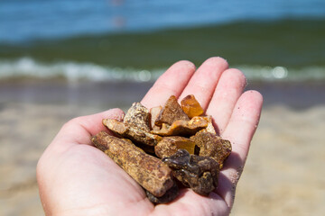 Amber not processed in sand against the background of sea waves.