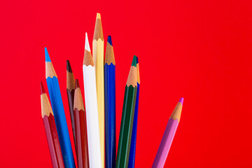 Many colorful pencils sticking up on deep red background