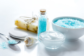 Plakat blue bath salt, body cream and shells for spa on white table background