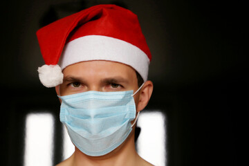 Portrait of man in medical face mask and Santa Claus hat. Christmas celebration during coronavirus pandemic