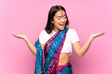 Young Indian woman with sari over isolated background holding copyspace with two hands