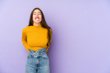Young caucasian woman isolated on purple background funny and friendly sticking out tongue.
