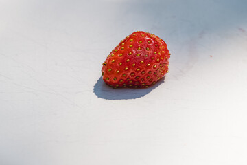 Single strawberry on a white surface